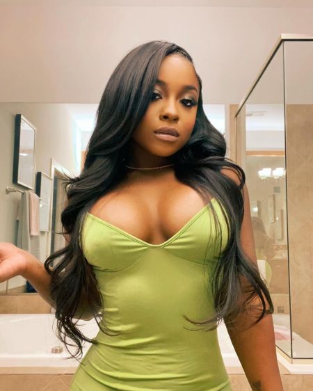 Reginae Carter poses a picture in a green dress.